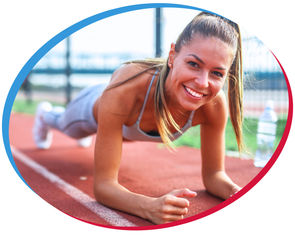 athletic woman doing pushups at a track and smiling up at the viewer 