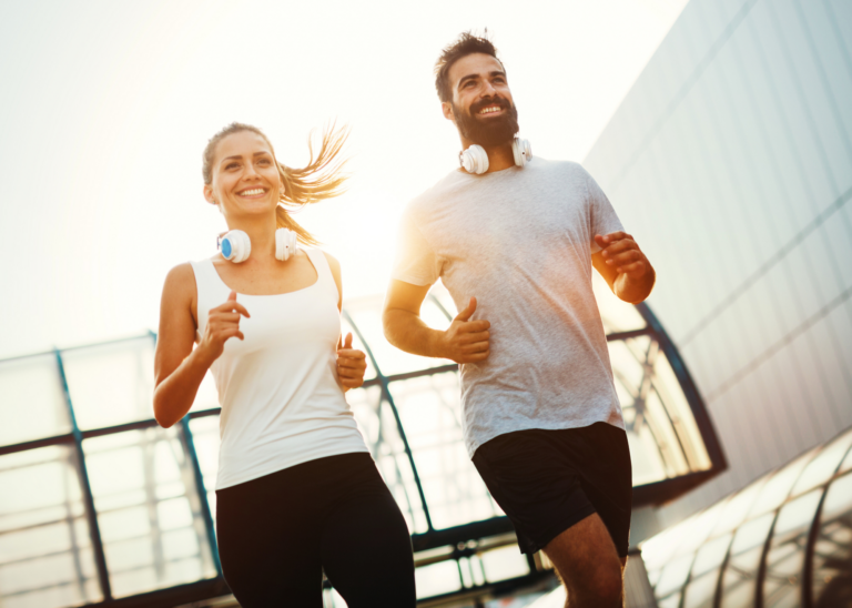 a young couple in shorts and sports tops, running together and looking off camera